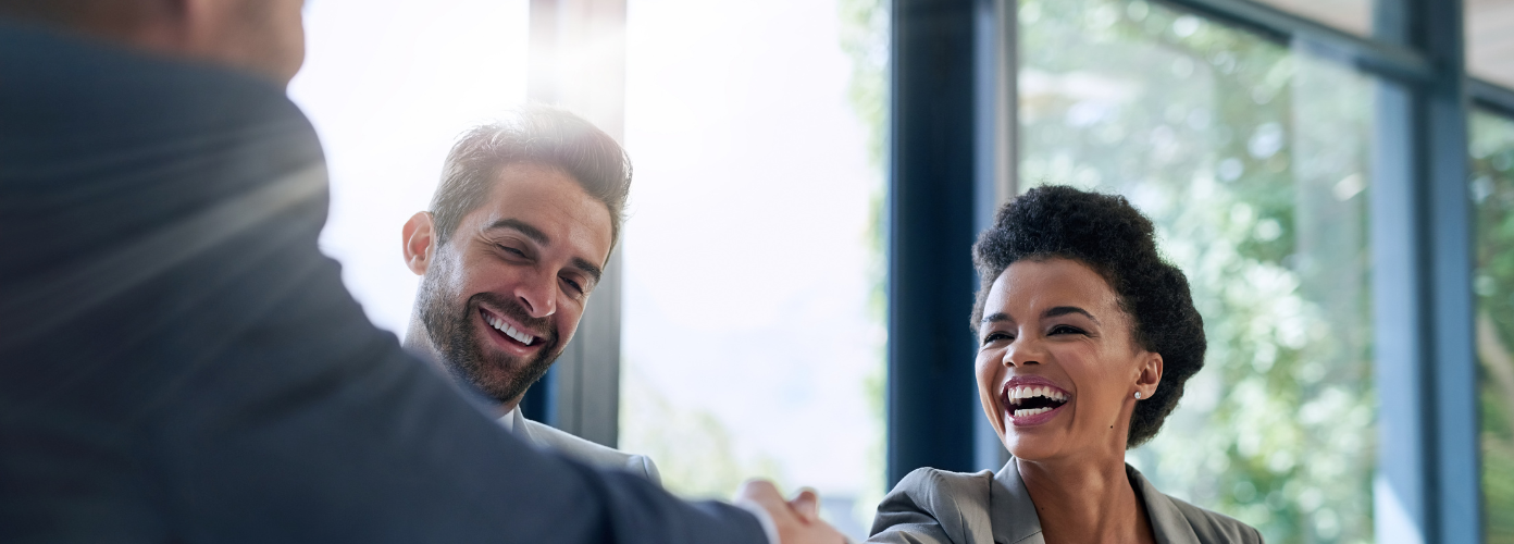 Two professionals shaking hands in an office, symbolizing a successful business deal.